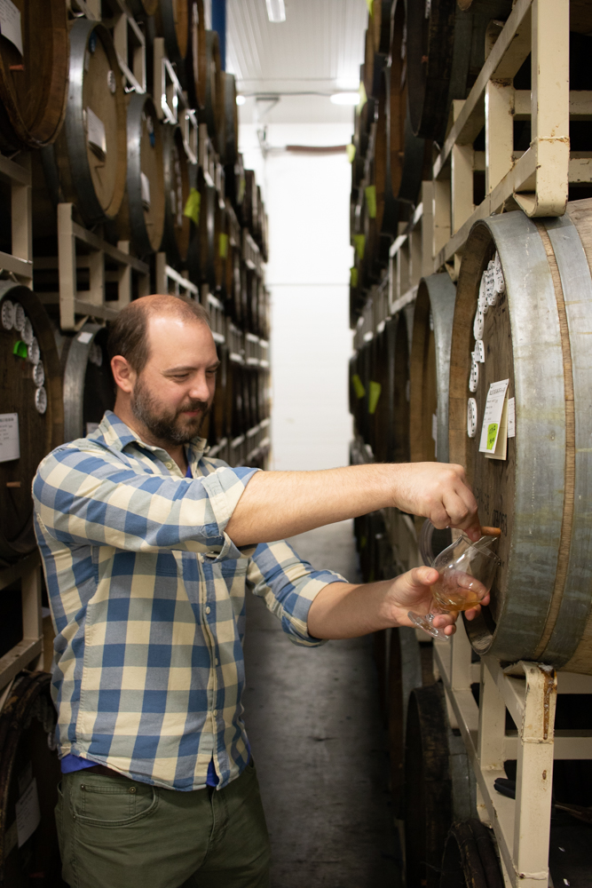 Kevin Martin pours a sample from a barrel in the Cascade blending facility.