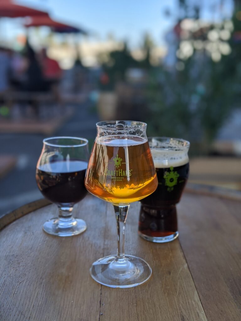Three CraftHaus beers in various glasses, sitting on a barrel table.