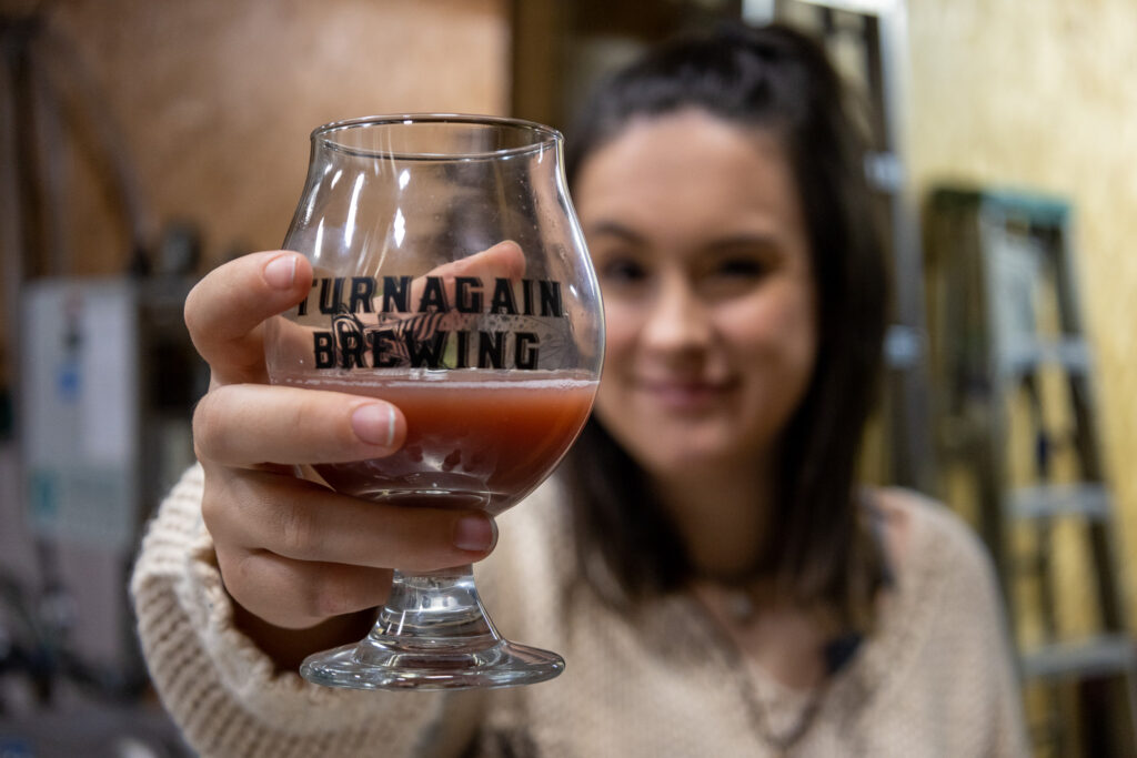Katie Mazos-Vega holding up a glass of Turnagain Brewing beer. Possibly the Framb Was.